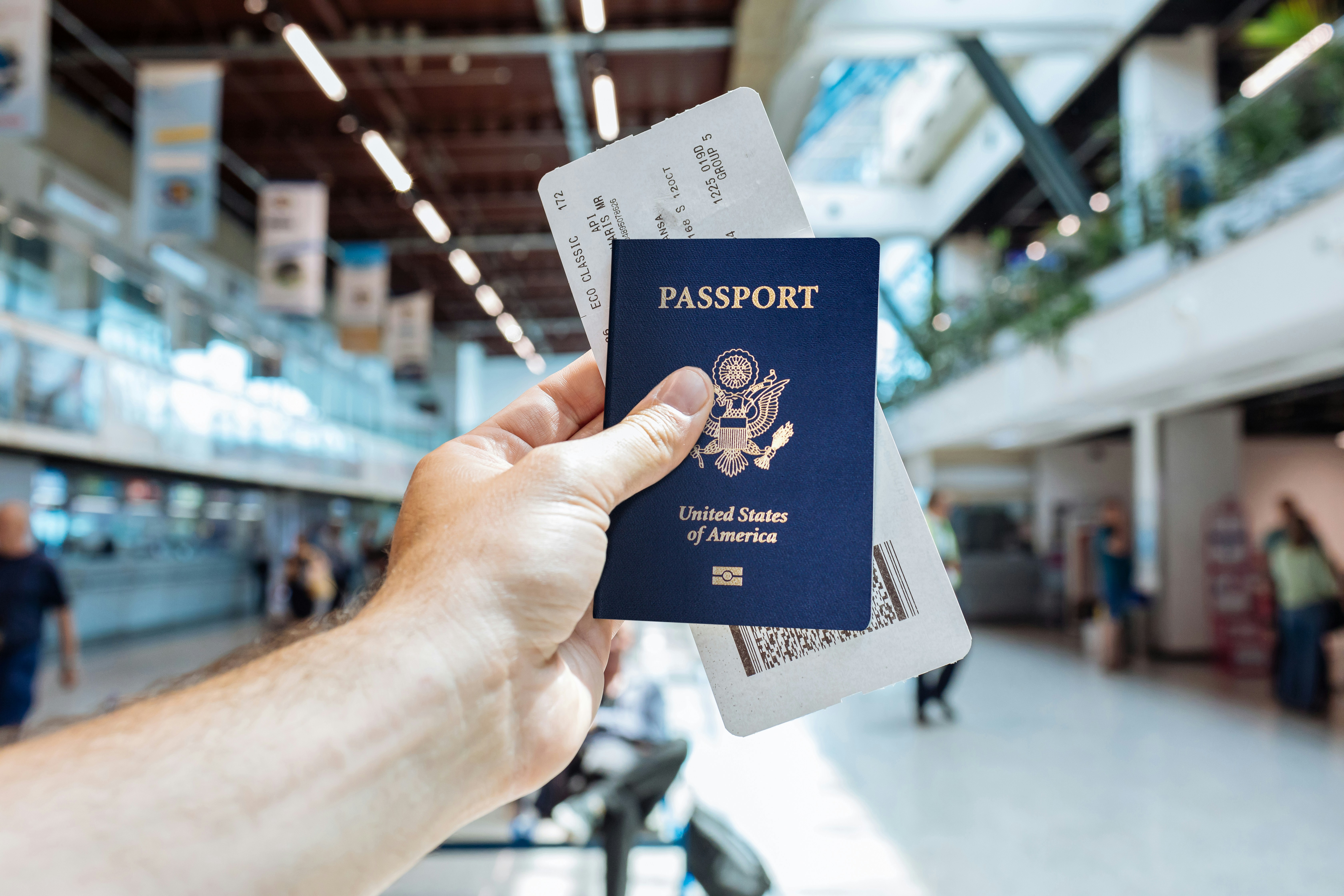 A passport and boarding pass held up in an airport
