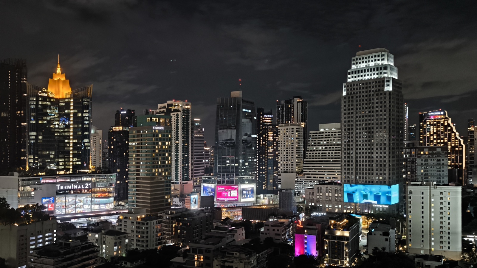Bangkok's illuminated Sukhumvit skyline seen across a dense residential neighbourhood at night