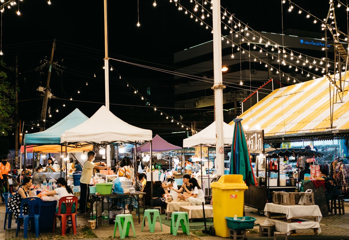 Busy evening market with illuminated food stalls in Thailand