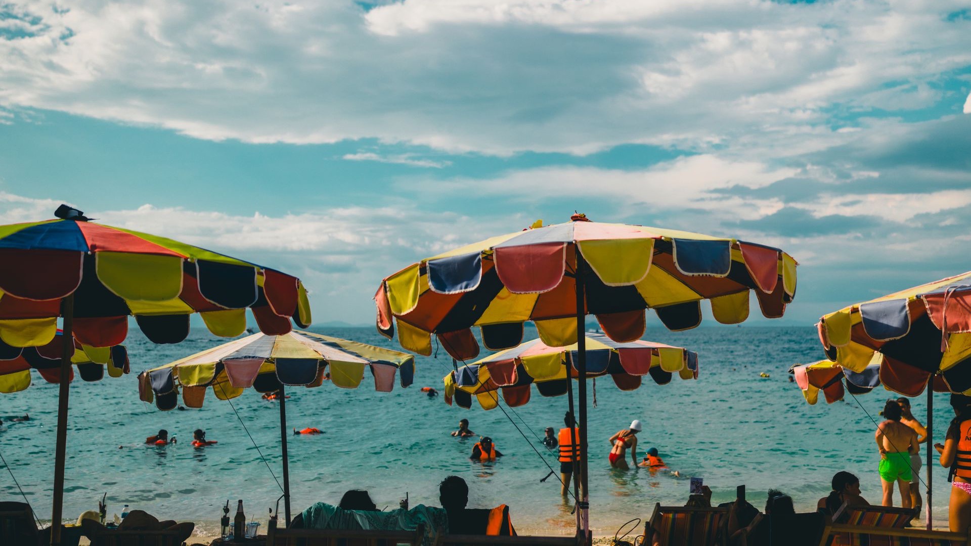 Palm-lined Patong Beach in Phuket with people relaxing by the sea