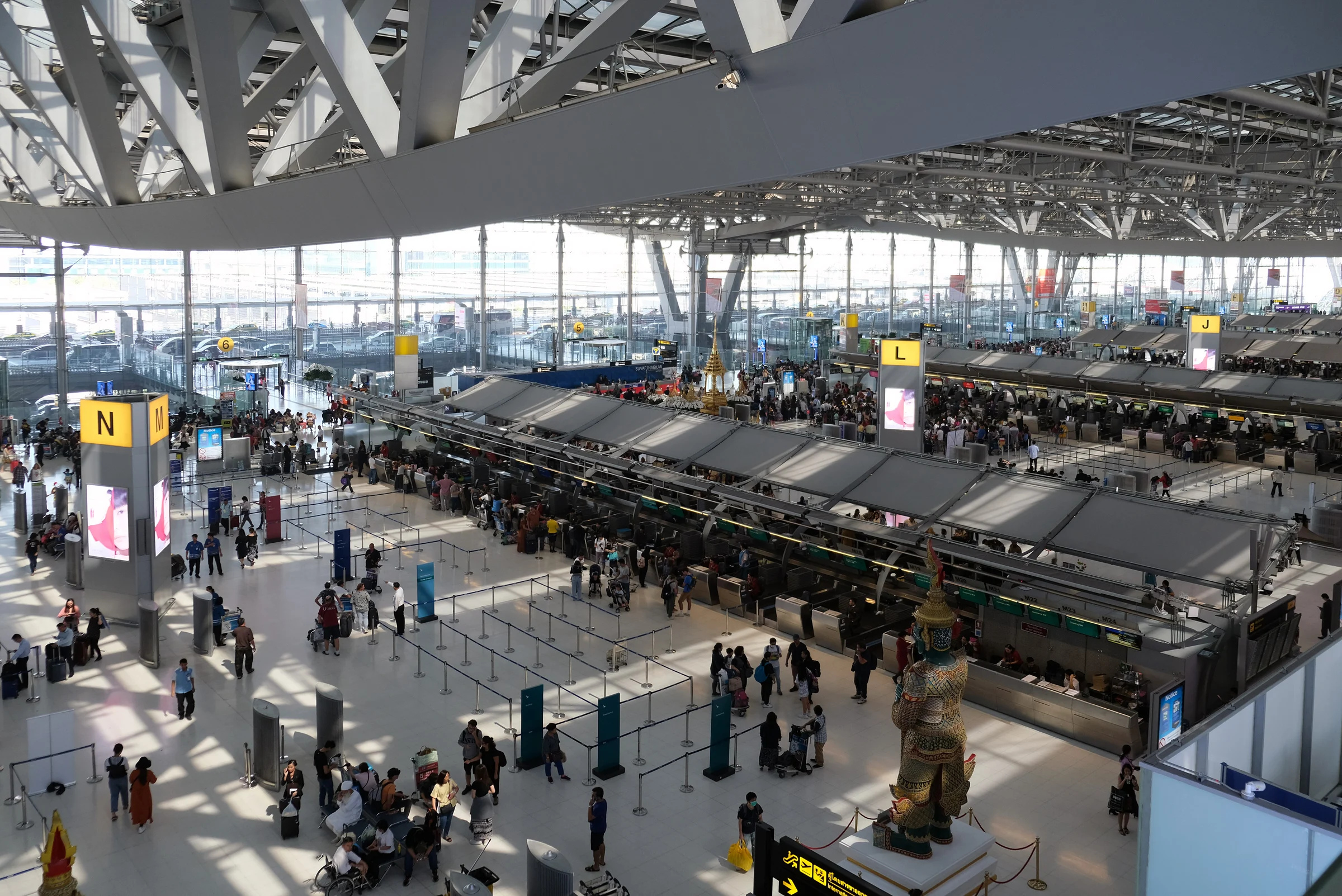Overhead view of the international check-in hall at Suvarnabhumi Airport in Bangkok, with passengers queuing at the counters