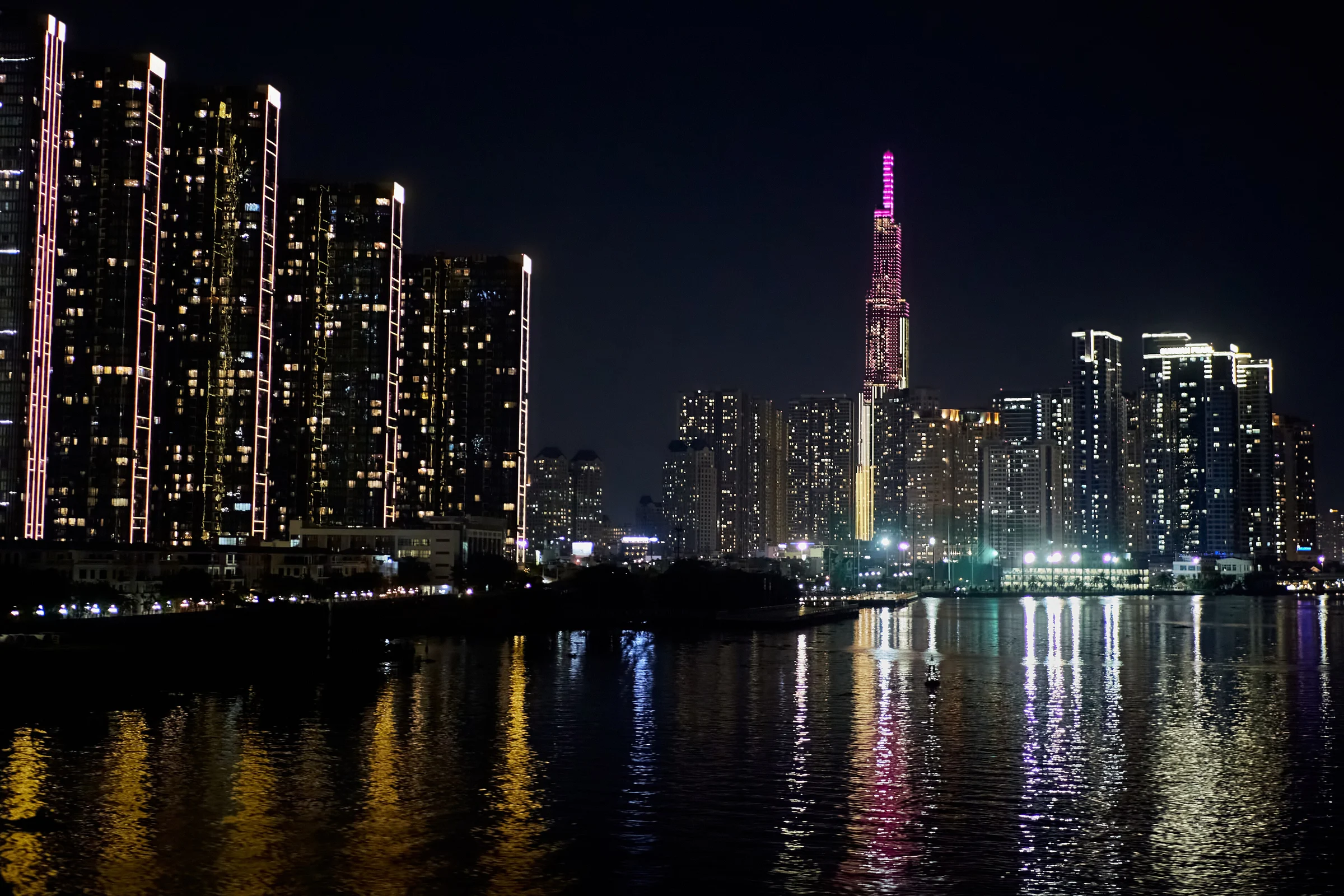 The Ho Chi Minh City skyline and Landmark 81 tower lit up at night, reflected in the Saigon River
